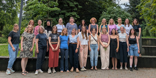 Team Sprache und Kommunikation 24 Menschen stehen in zwei Reihen versetzt hintereinander und schauen in die Kamera