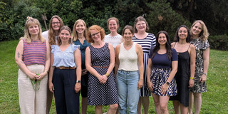 Team PostDocs/Docs/WiMi 11 Menschen stehen in zwei Reihen versetzt hintereinander und schauen in die Kamera
