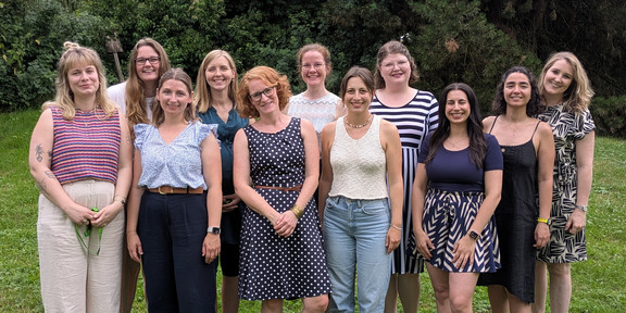 Team PostDocs/Docs/WiMi 11 Menschen stehen in zwei Reihen versetzt hintereinander und schauen in die Kamera