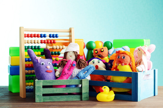 Bunte Handpuppen und Quietscheentchen vor einem Rechenschieber und Bauklötzen.